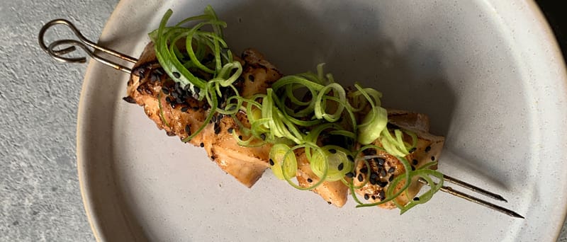 Skewered chicken topped with green onions and sesame seeds