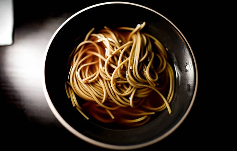 Soba noodles served in a black bowl.